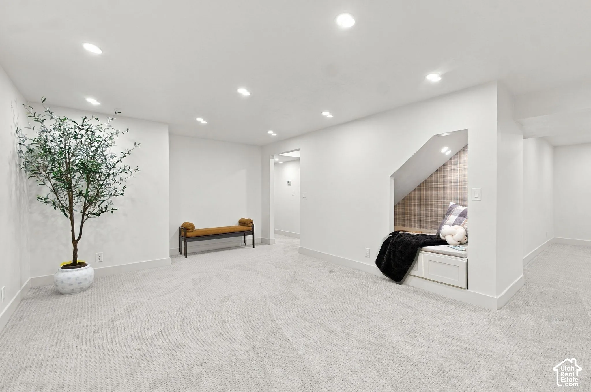 Open-concept room featuring neutral carpeted flooring, recessed lighting, and a built-in recessed nook with integrated storage cabinetry