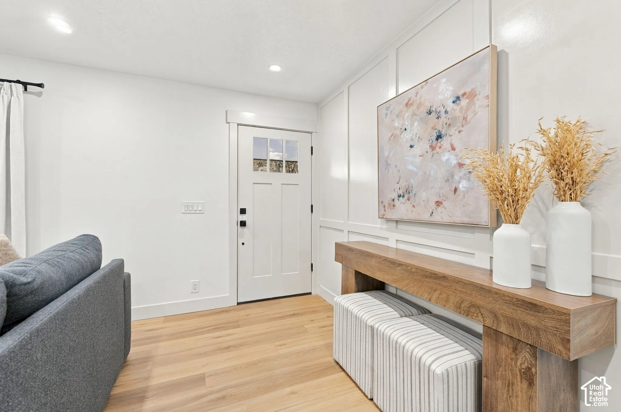 Entryway featuring wood-finish flooring, recessed lighting, and wall wainscoting, complemented by an exterior door with glass pane detail