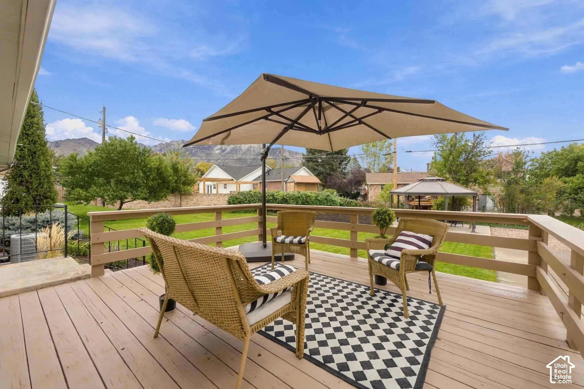 Elevated deck featuring wood-finish flooring and horizontal rail fencing, overlooking a manicured lawn with mountain backdrop