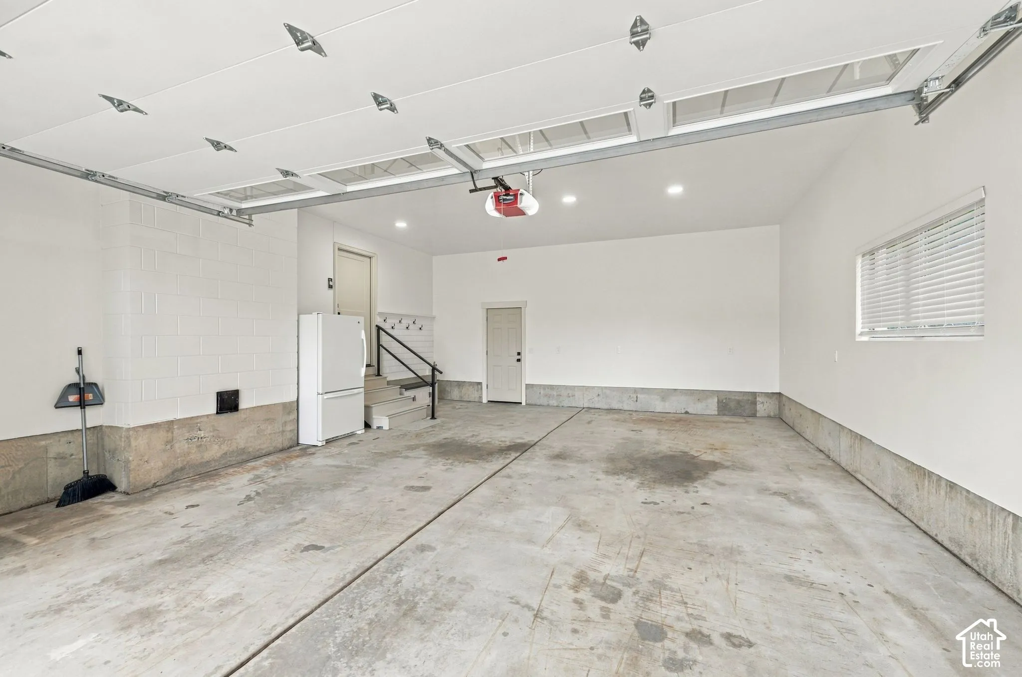 Multi-car garage featuring recessed lighting, a concrete floor, painted concrete block walls, and elevated entry stairs with a handrail
