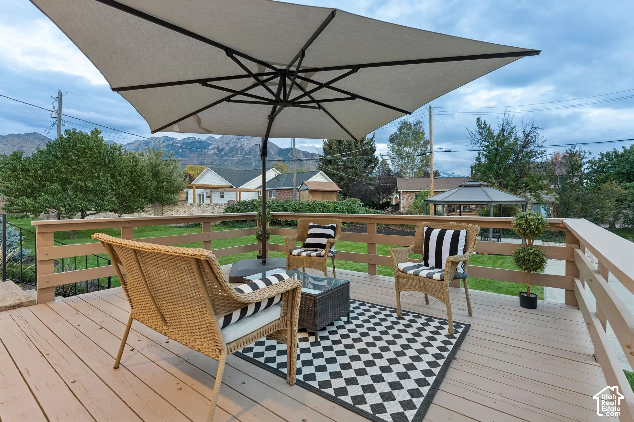 Elevated deck featuring horizontal wood-finish railings, grass lawn, and mountain backdrop