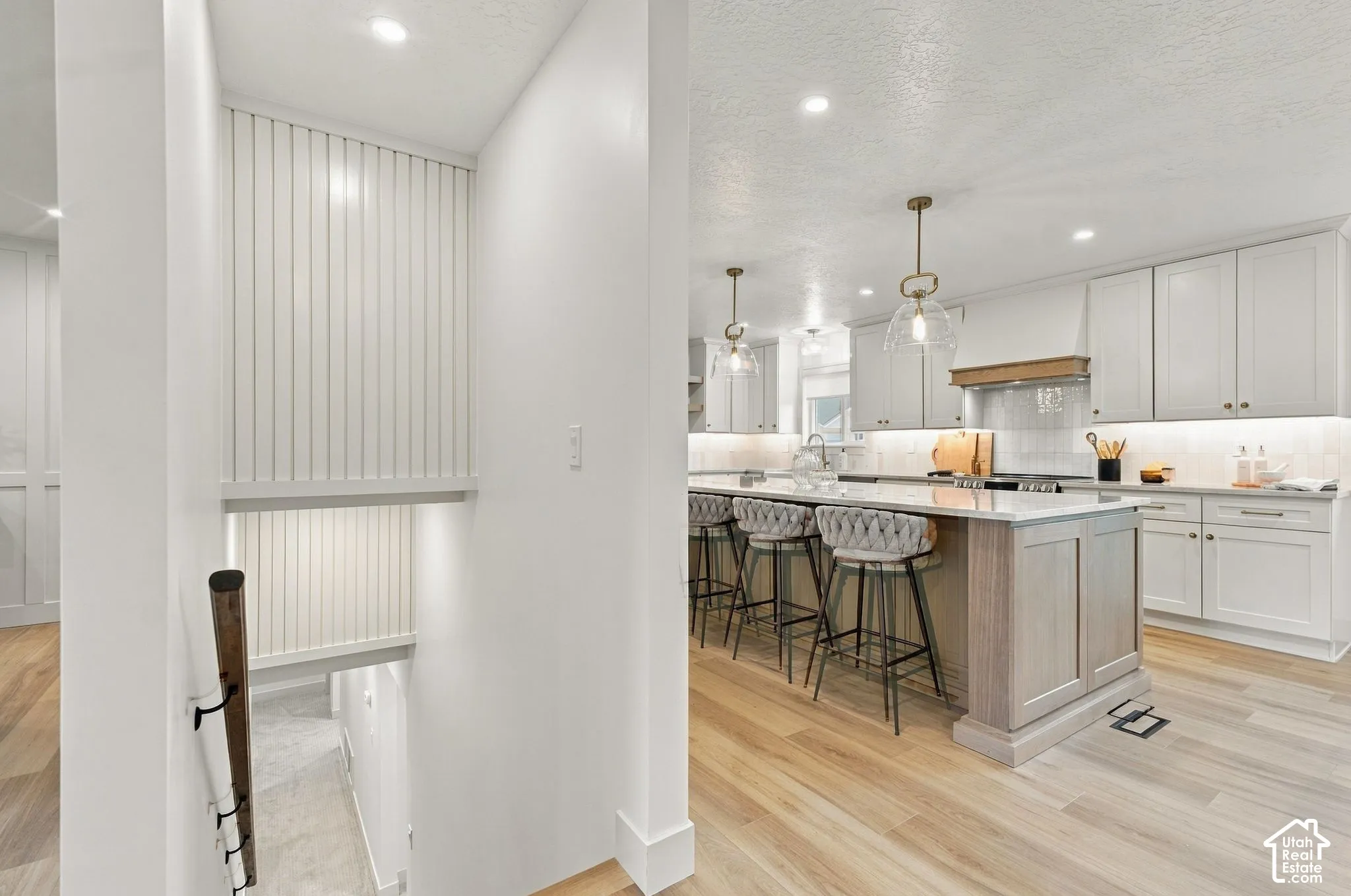 Kitchen featuring a central island with a stone countertop, cabinetry with shaker-style doors, wood-finish flooring, and recessed ceiling lighting