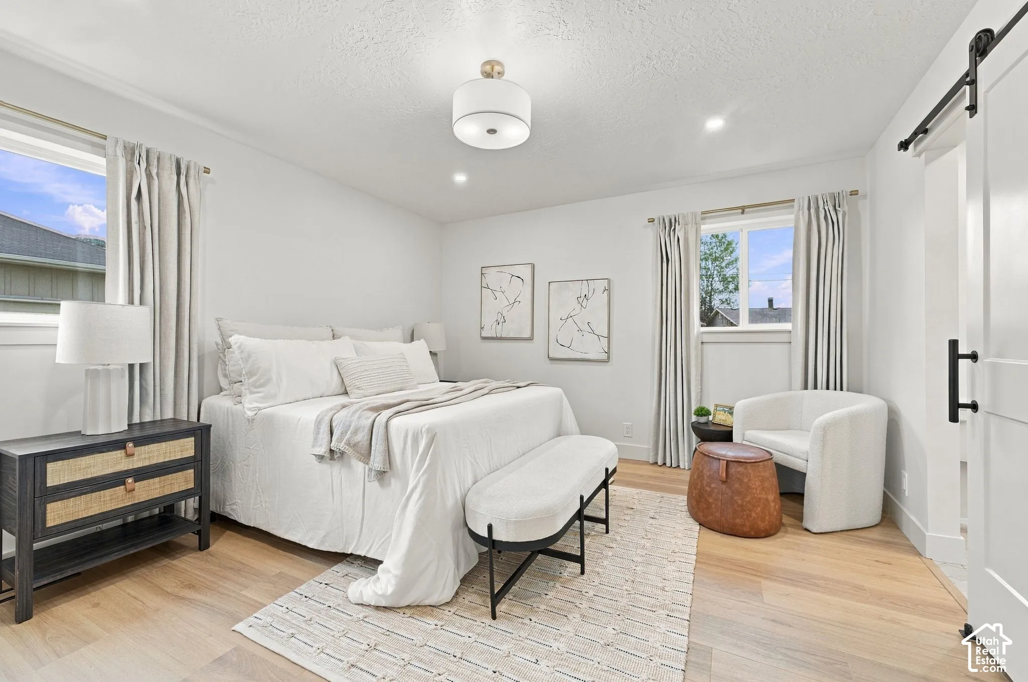 Wood-finish flooring, white sliding barn door with black iron hardware, recessed lighting, and drum-style ceiling fixture