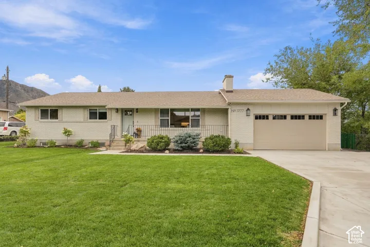 Single-story brick exterior residence featuring a concrete driveway, attached multi-car garage, covered entryway, and landscaped front lawn