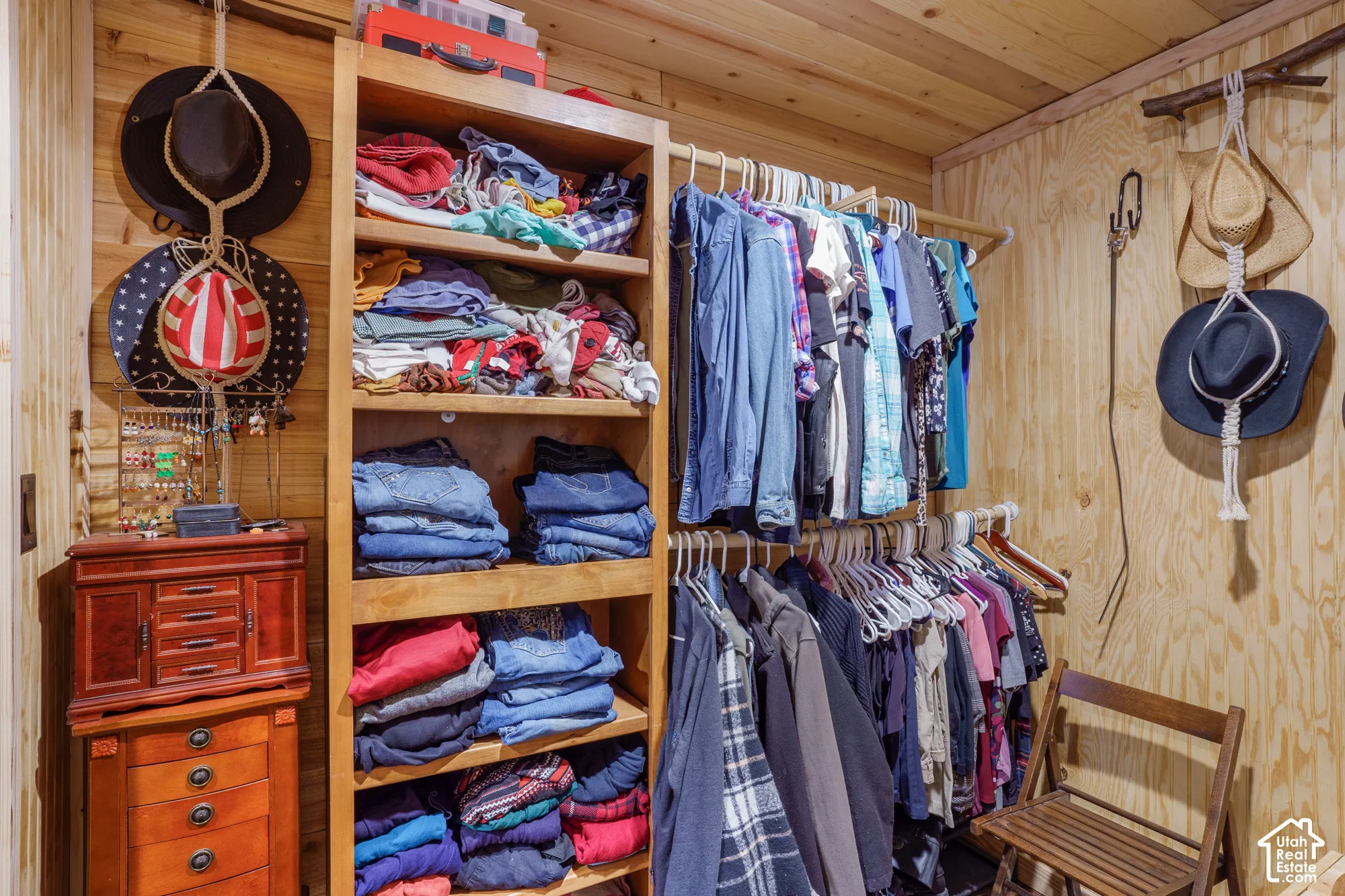Walk-in closet featuring natural wood-paneled walls, built-in open shelving, and dual-tier clothing rods