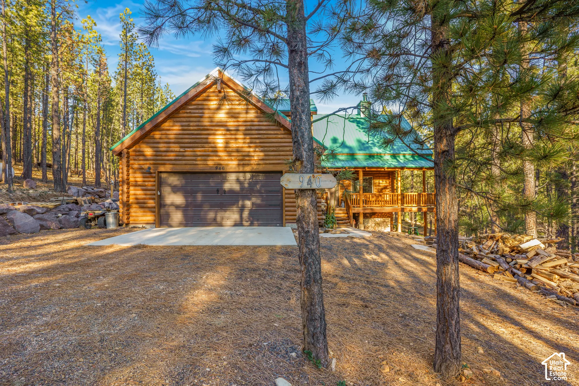 Log cabin exterior featuring horizontal log siding, a metal roof, an attached garage, and a wood-railed deck