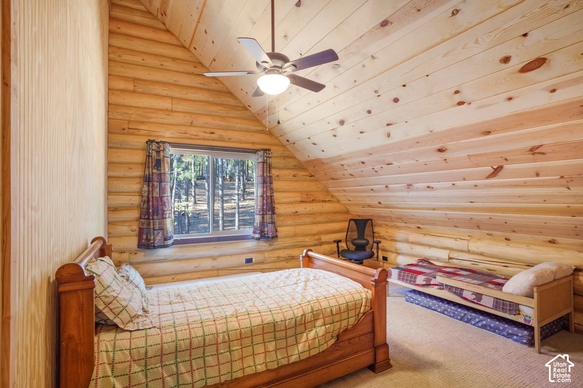 Vaulted ceiling with exposed log walls, natural wood planking, and an integrated ceiling fan