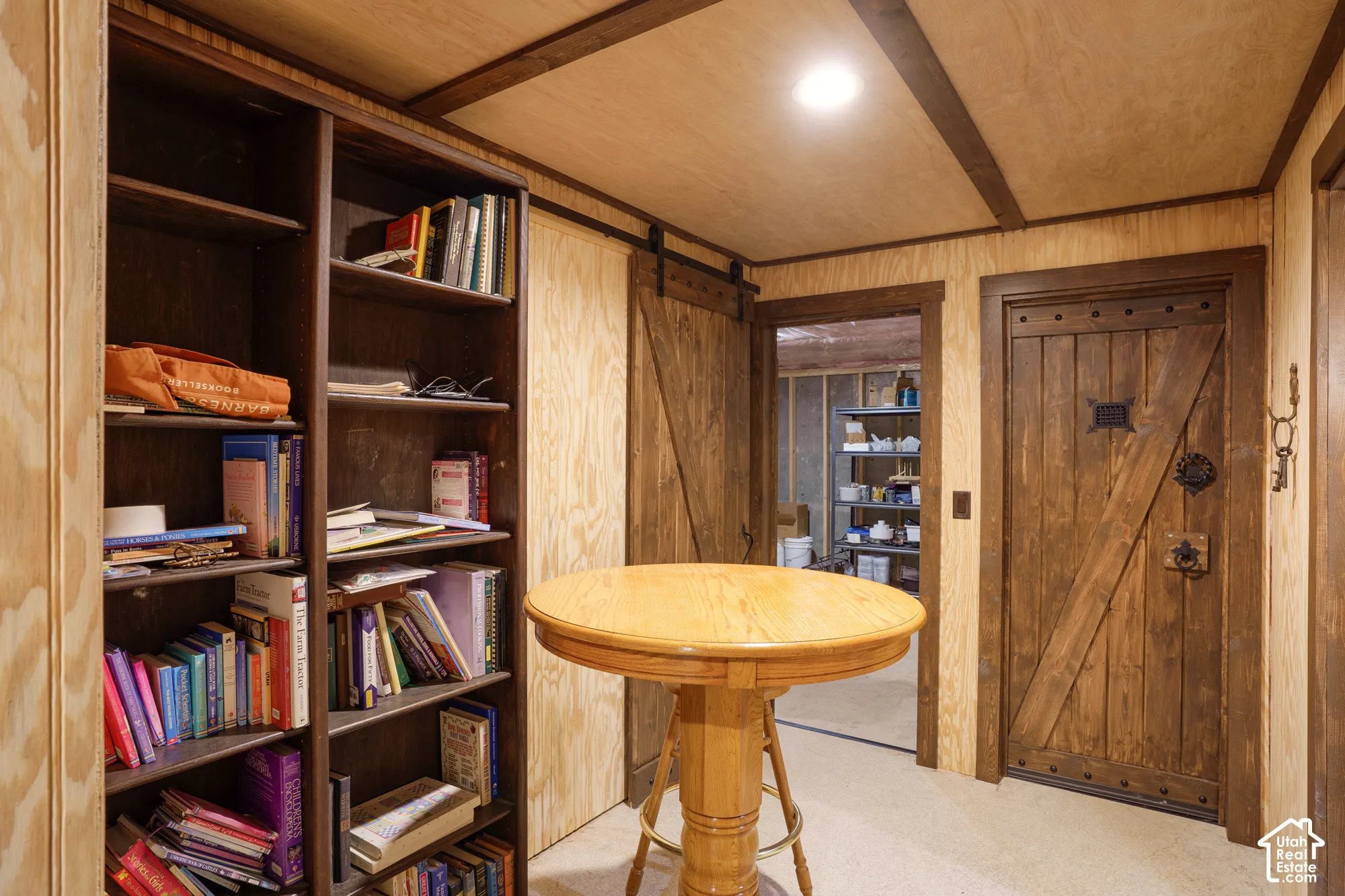 Built-in dark-toned shelving, rustic wood-plank door with iron hardware, sliding barn-style door, and recessed ceiling lighting