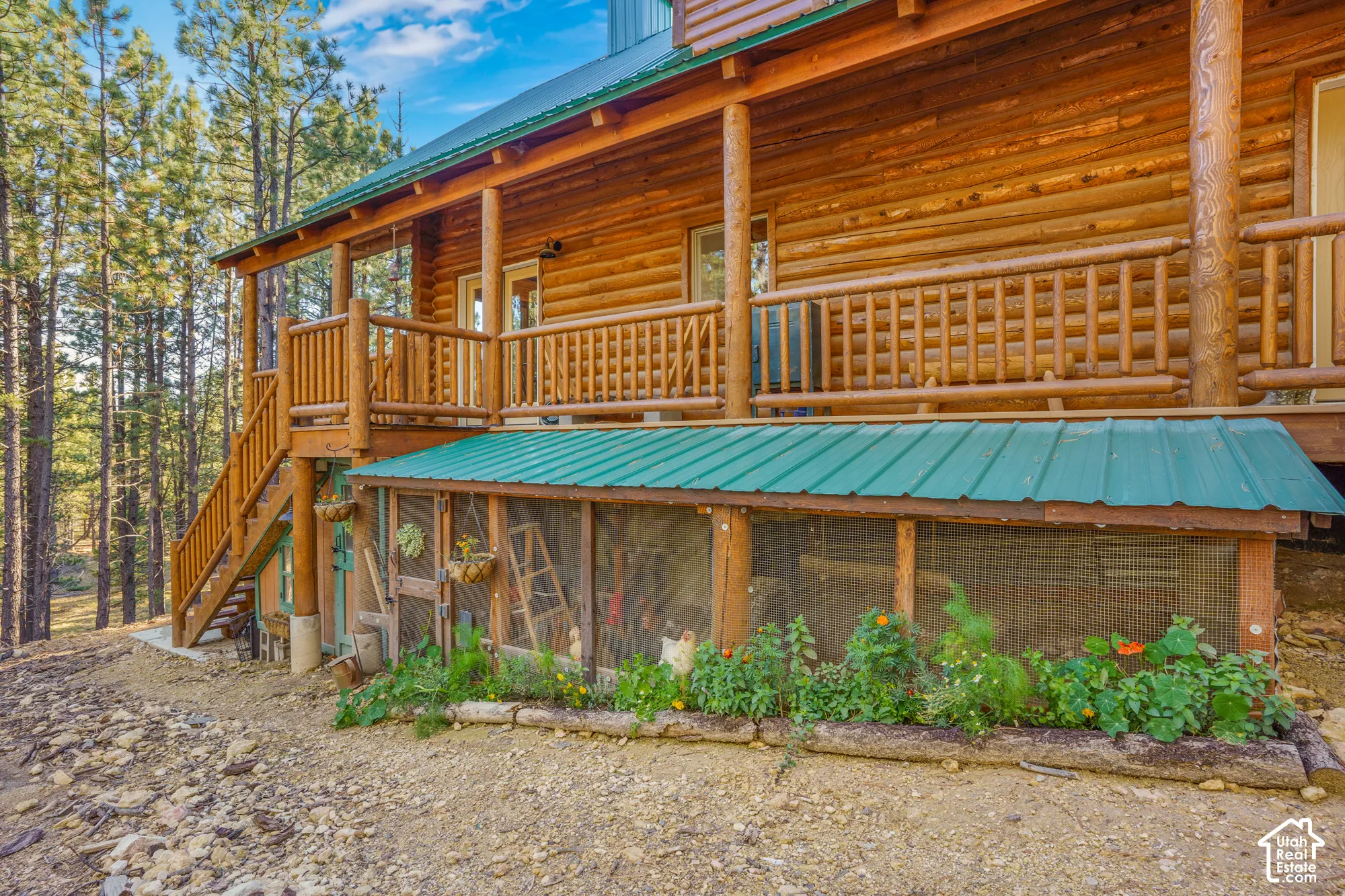 Log-constructed exterior featuring an elevated wooden deck with railing, a metal roof, and an integrated lower-level enclosure with wire mesh siding