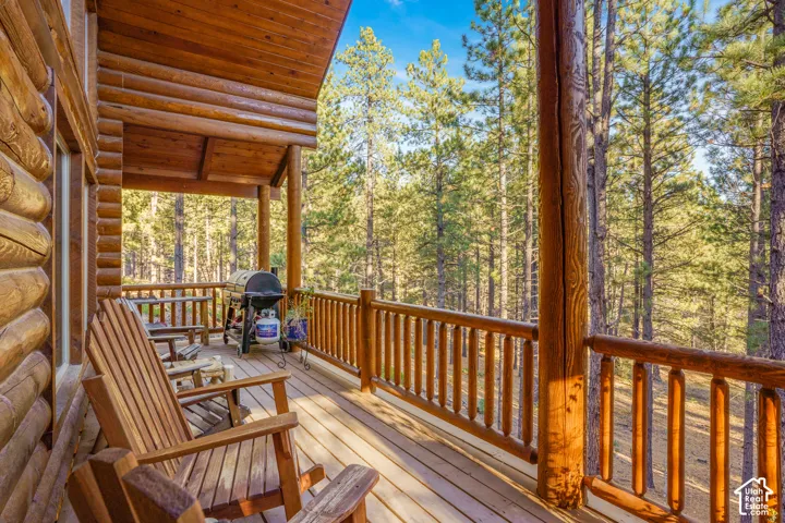Covered timber-frame deck featuring log-style siding, wooden decking, and railing with vertical balusters