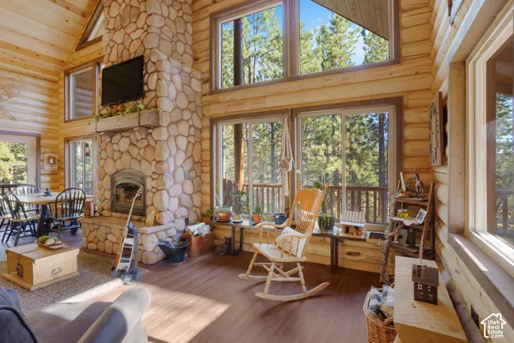 Log wall construction featuring vaulted ceilings, floor-to-ceiling stone fireplace with a timber mantel, and expansive multi-pane windows
