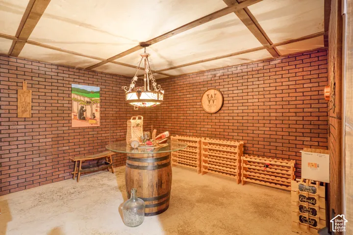 Exposed brick wall finishes, overhead beam ceiling grid, and decorative wrought-iron style chandelier