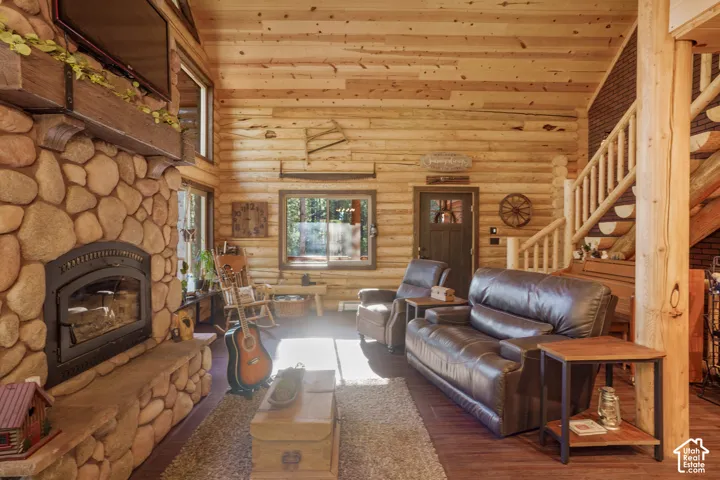 Log wall construction, vaulted wood-plank ceiling, full-height river rock fireplace with timber mantel, and custom log staircase