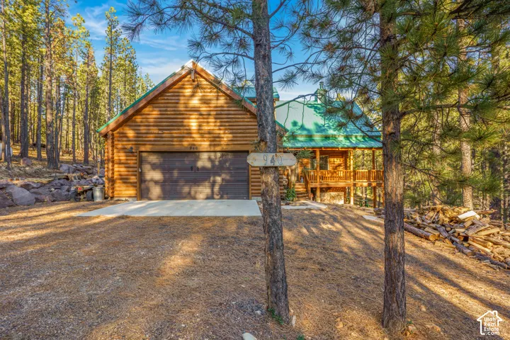 Log cabin exterior featuring horizontal log siding, a metal roof, an attached garage, and a wood-railed deck