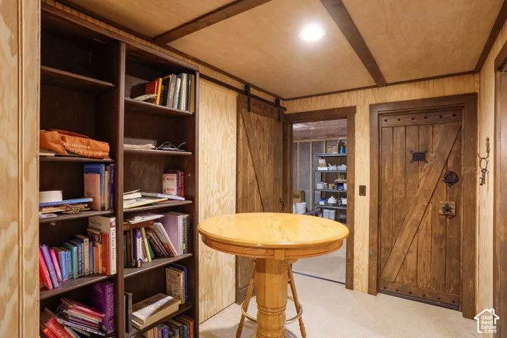 Built-in dark-toned shelving, rustic wood-plank door with iron hardware, sliding barn-style door, and recessed ceiling lighting