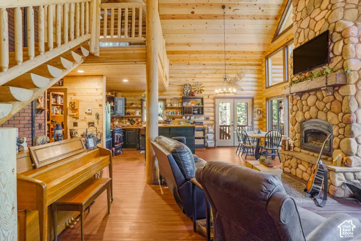 Log-construction interior featuring a floor-to-ceiling river stone fireplace, vaulted tongue-and-groove wood ceilings, a prominent log staircase, and wood-finish flooring