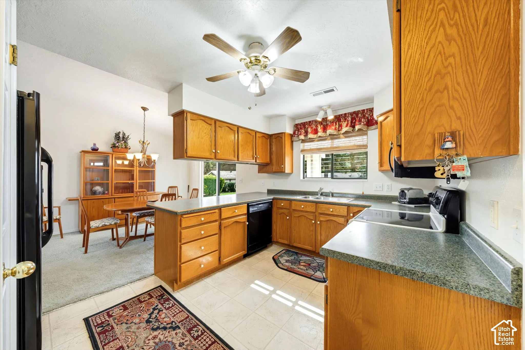 Kitchen featuring natural wood cabinetry, solid surface countertops, an integrated double-basin sink, and a ceiling-mounted fan