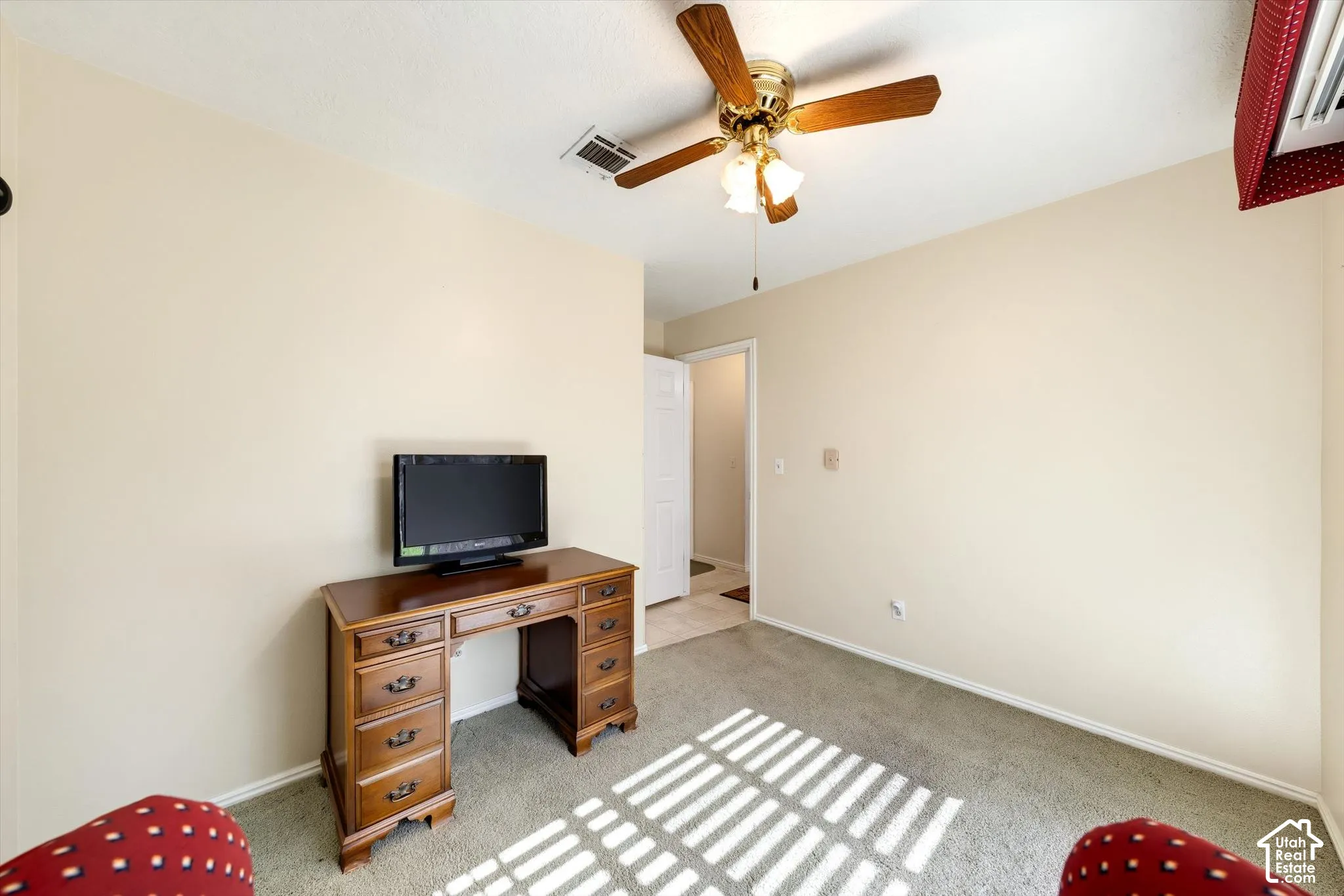 Neutral-toned walls, wall-to-wall carpeting, and a ceiling fan with integrated light fixture