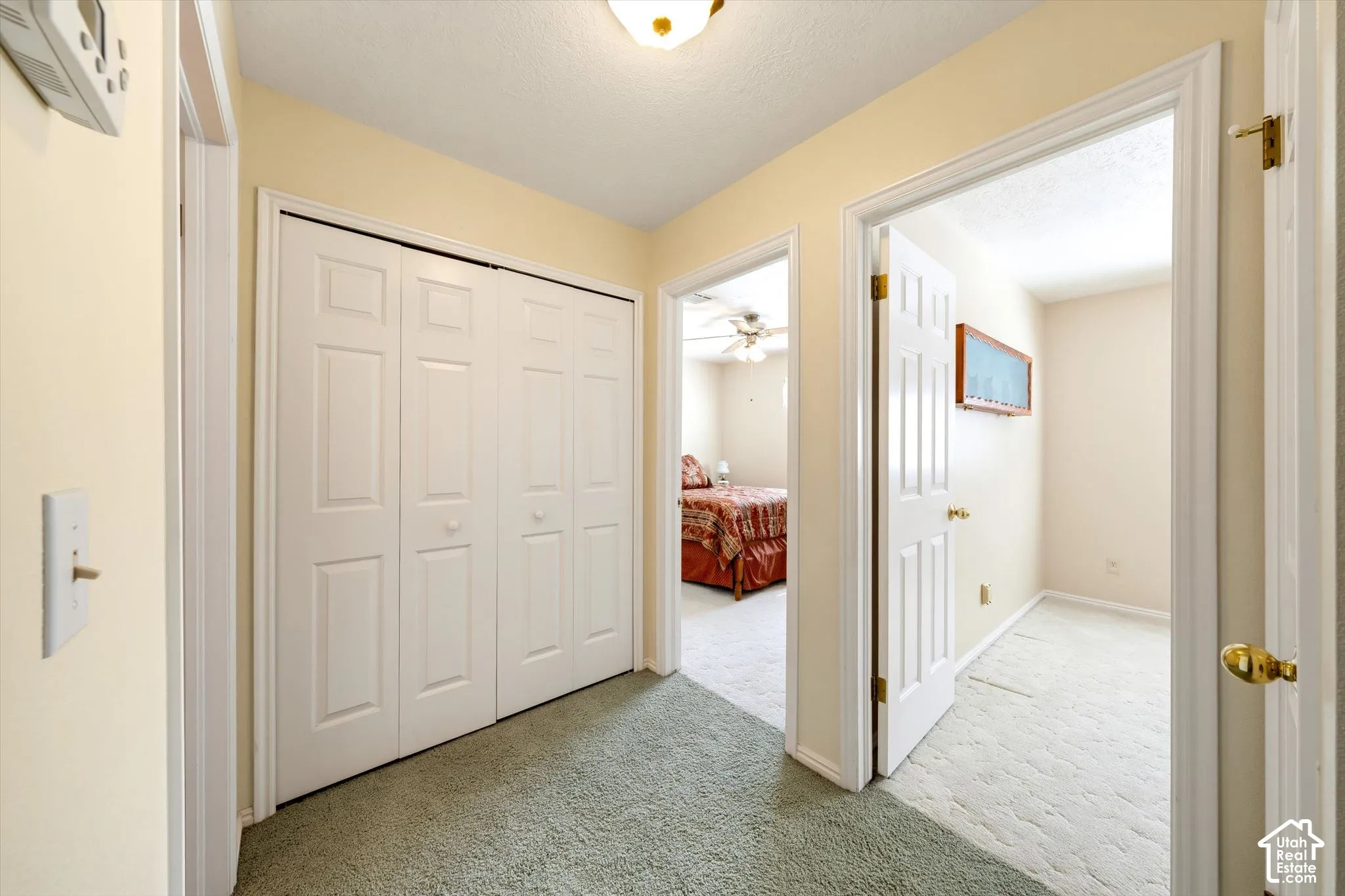 Hallway featuring white six-panel closet doors, crisp white door casings, neutral wall coloring, and a central overhead light fixture