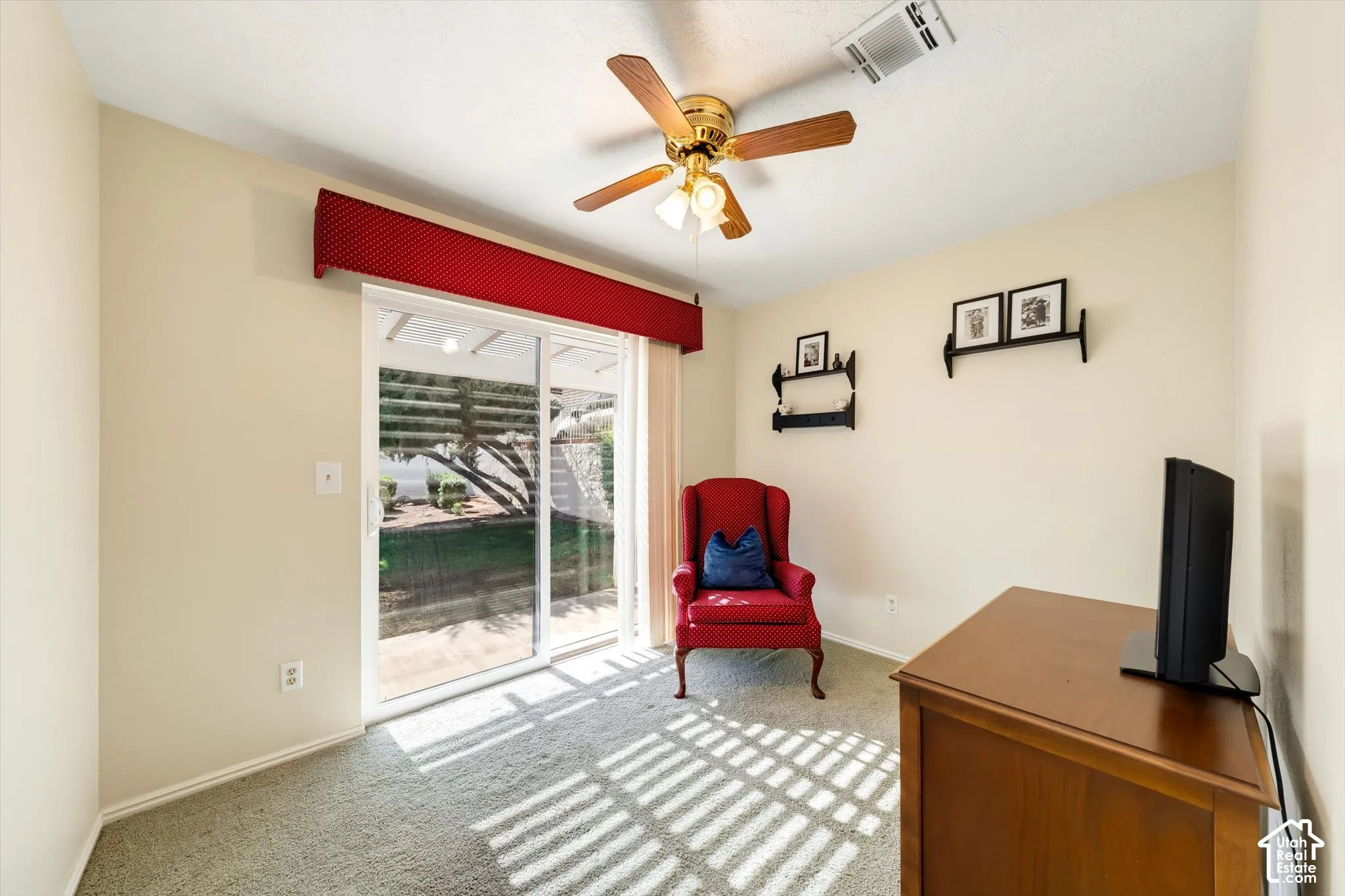 Sliding glass door with integrated valance, ceiling fan with light fixture, and neutral carpeting