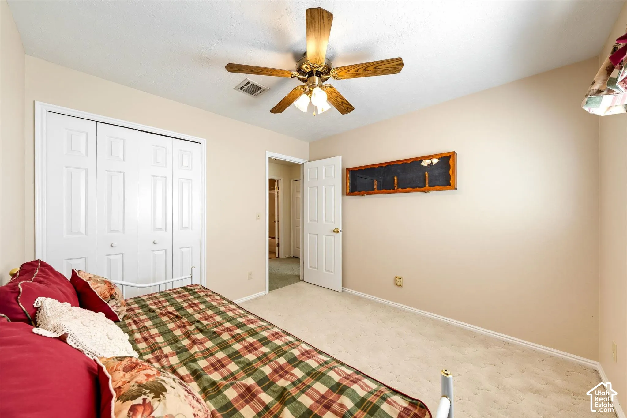 Neutral-toned interior featuring wall-to-wall carpeting, a multi-blade ceiling fan with integrated lighting, and white six-panel closet doors