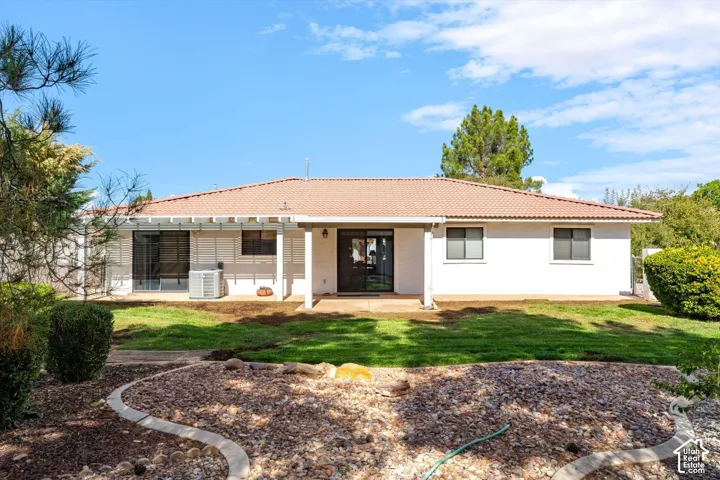 Exterior rear elevation featuring a concrete patio, pergola, tile roof, and rock garden landscaping