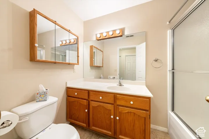 Bathroom vanity with a solid-surface countertop, wood cabinetry, large vanity mirror, tri-fold medicine cabinet, and a shower with a sliding glass enclosure