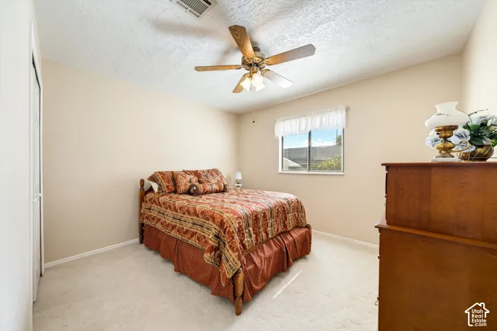 Neutral-toned interior featuring wall-to-wall carpeting, a ceiling fan with integrated lighting, and a closet with sliding doors