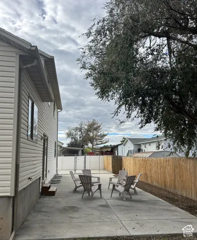 Concrete patio space enclosed by a combination of wood privacy fencing and chain-link fencing, featuring light-colored horizontal exterior siding