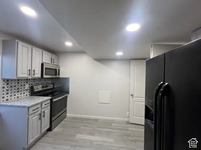Kitchen featuring white shaker-style cabinetry, patterned tile backsplash, stone-finish countertops, recessed lighting, and wood-finish flooring
