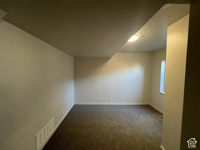 Neutral-toned interior room featuring wall-to-wall carpeting, smooth-finish ceiling, and a single window