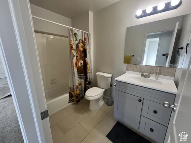 Bathroom featuring a grey shaker-style vanity with a solid-surface countertop, an integrated sink, a rectangular vanity mirror, four-light vanity fixture, and a tile-surround shower and tub combination