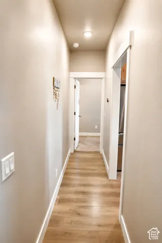 Hallway featuring wood-finish flooring, white door casing, and recessed ceiling lighting
