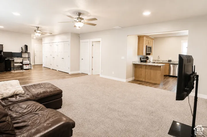 Spacious interior featuring wood-finish flooring, neutral carpeting, recessed lighting, dual ceiling fans, and built-in cabinetry
