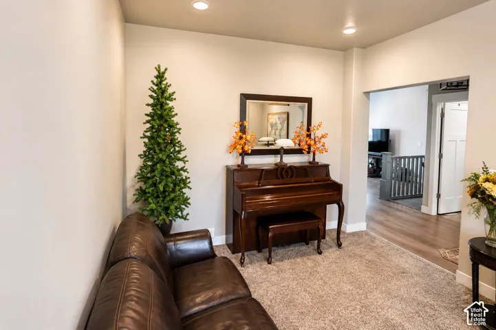 Neutral-toned interior space featuring recessed ceiling lighting, wall-to-wall carpeting, and wood-finish flooring