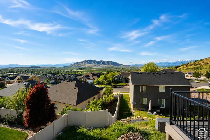 Elevated deck with black metal railing, overlooking a residential neighborhood featuring mountain and valley scenery
