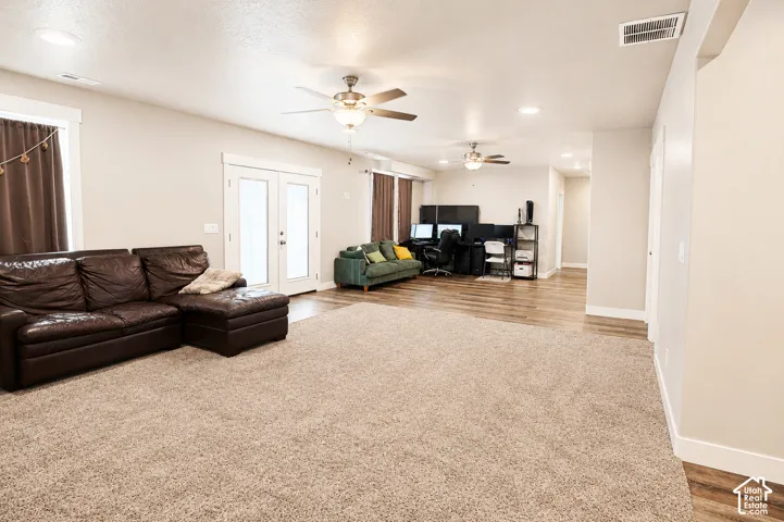 Open-concept area featuring recessed lighting, dual ceiling fans, wood-finish flooring, wall-to-wall carpeting, and double glass-pane doors
