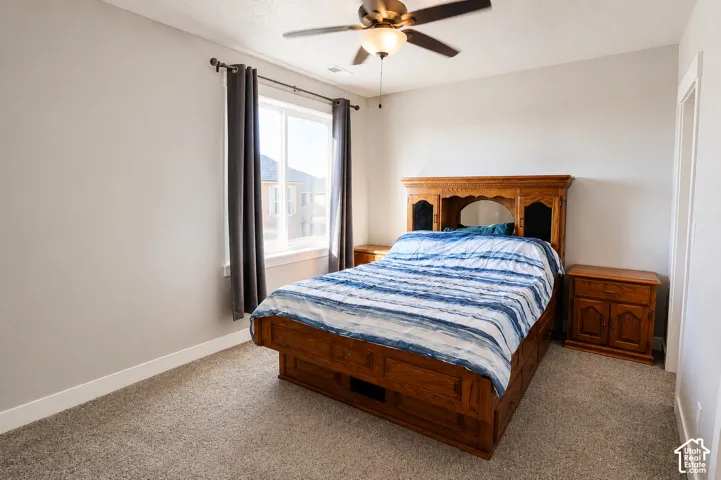 Neutral wall tones, carpeting, double-pane window, and a ceiling-mounted light fixture with fan