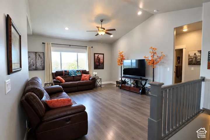 Vaulted ceilings featuring recessed lighting, wood-finish flooring, and a painted wooden staircase railing