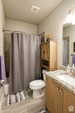 Bathroom featuring wood-finish flooring, a vanity with a stone-composite countertop, an integrated sink, and tile-surround tub