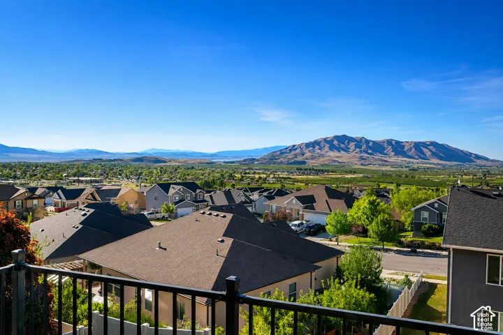 Elevated metal railing overlooking a panoramic landscape featuring a expansive mountain backdrop and sprawling valley scenery