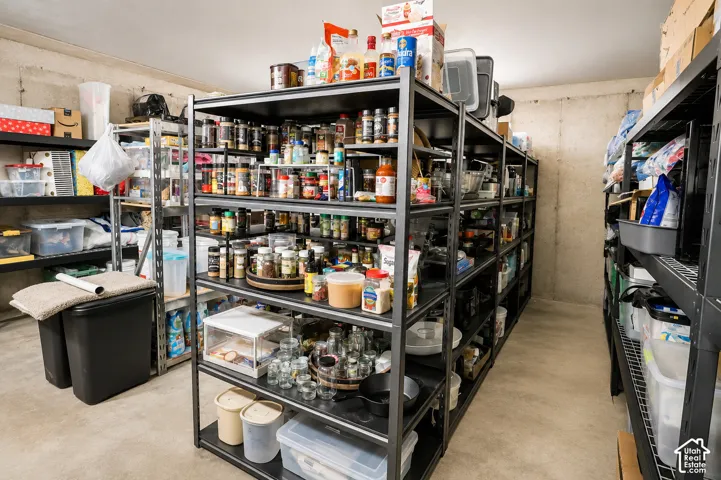 Storage space featuring concrete walls and flooring with industrial metal shelving units