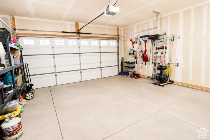 Multi-car garage featuring a sectional door with windows, concrete flooring, and an automated overhead garage door opener