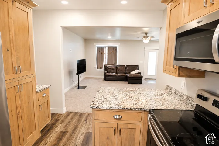 Kitchen featuring light-finish cabinetry, stone-style countertops, wood-finish flooring, and stainless steel appliances