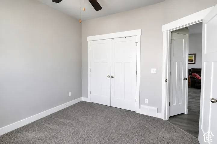 Neutral-toned interior featuring wall-to-wall carpeting, white shaker-style doors, craftsman-style door casings, and a ceiling fan with light fixture