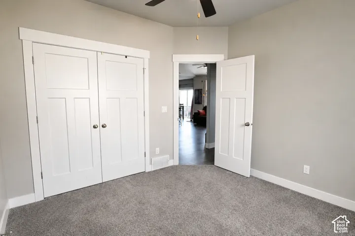 Room featuring neutral wall tones, plush wall-to-wall carpeting, shaker-style panel doors, and a ceiling fan