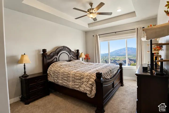 Tray ceiling, neutral wall tones, carpeted flooring, built-in recessed lighting, and large picture window with mountain scenery
