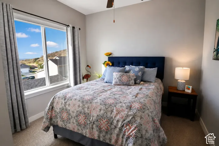 Neutral-toned room featuring a large sliding window, carpeted flooring, and a ceiling fan