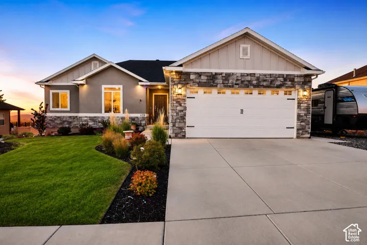 Single-story exterior featuring a stone veneer facade, vertical siding, an attached three-car garage, and manicured landscaping