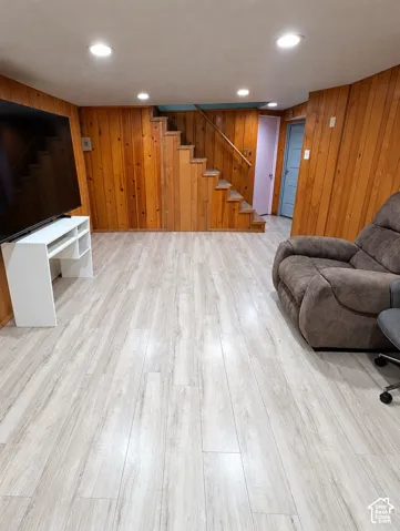 Wood-paneled walls, wood-finish flooring, recessed lighting, and a staircase with a wooden handrail